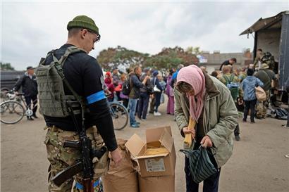 Ein ukrainischer Soldat des Sophia-Bataillons verteilt humanitäre Hilfe an eine Frau in Isjum
