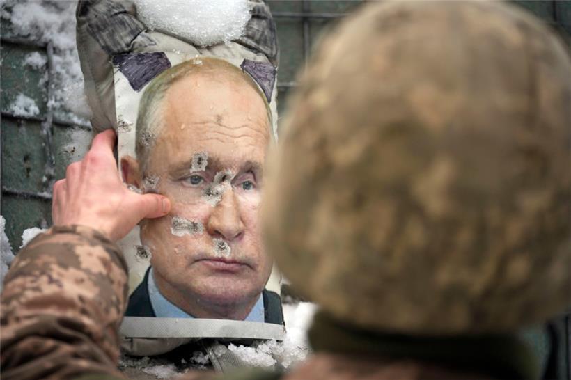 Ein ukrainischer Soldat justiert ein von Kugeln durchlöchertes Bild des russischen Präsidenten Putin während eines Interviews mit Medienvertretern an einer Frontlinie
