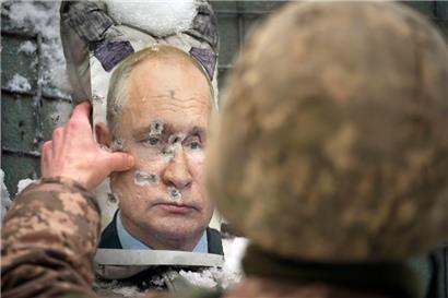 Ein ukrainischer Soldat justiert ein von Kugeln durchlöchertes Bild des russischen Präsidenten Putin während eines Interviews mit Medienvertretern an einer Frontlinie
