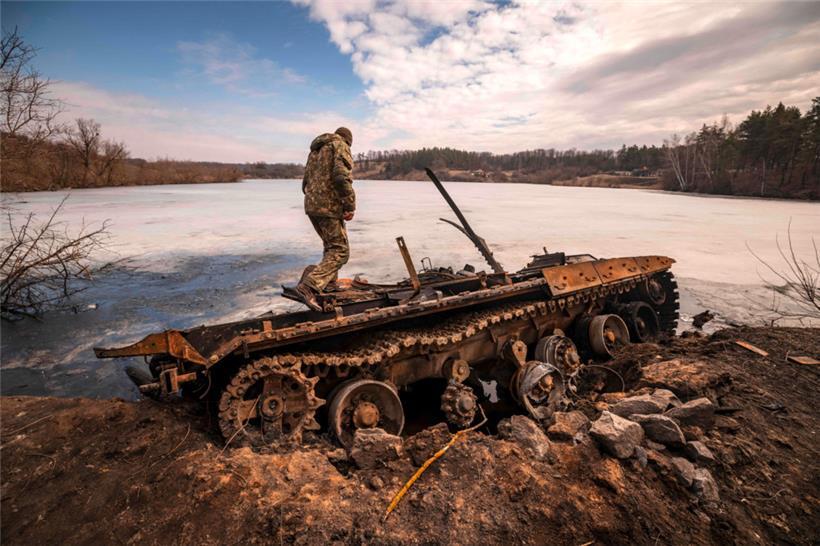 Ein ukrainischer Soldat steht auf einem zerstörten russischen Panzer in der nordöstlichen Stadt Trostianets
