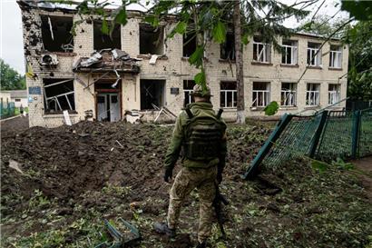 Ein ukrainischer Soldat steht vor einem Schulgebäude in Tschuhujiw, das durch Beschuss des russischen Militärs zerstört wurde
