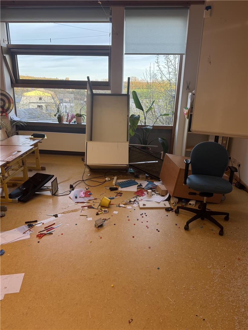 Umgeworfener Schreibtisch mit liegendem Computerbildschirm auf dem Boden, Chaos im Arbeitszimmer sichtbar