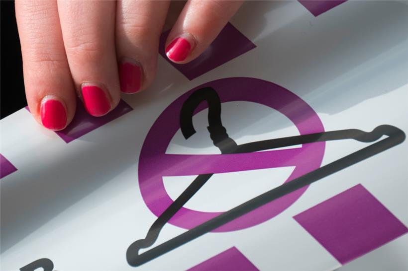 Eine Aktivistin hält ein Band mit einem durchgestrichenen Kleiderbügel. Früher haben manche Frauen mit dem Kleiderbügel eine ungewollte Schwangerschaft abgebrochen.
