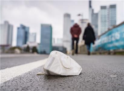 Eine Corona-Maske liegt auf einem nassen Gehweg
