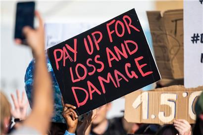 Eine Demonstrantin auf dem UN-Klimagipfel hält ein Plakat mit der Aufschrift „Pay up for loss and damage“
