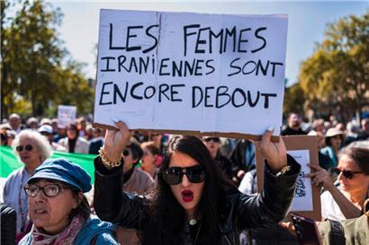Eine Demonstrantin trägt ein Plakat mit der Aufschrift „Iranische Frauen stehen immer noch aufrecht“ während eines Marsches zum zweiten Jahrestag einer Protestbewegung, die durch den Tod der 22-jährigen Mahsa Amini in Gewahrsam ausgelöst wurde. Sie war am 15. September 2024 in Paris wegen angeblicher Verletzung der Kleiderordnung für Frauen am Place de la Bastille verhaftet…
