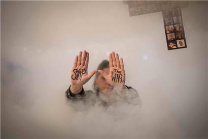 Eine Demonstrantin zeigt während eines Protests den auf ihre Handflächen geschriebenen Schriftzug „Stoppt den Krieg“

