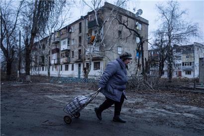 Eine Einheimische geht zur Verteilungsstelle für humanitäre Hilfe vor einem Haus, das nach ukrainischen Angaben durch russischen Beschuss beschädigt wurde.
