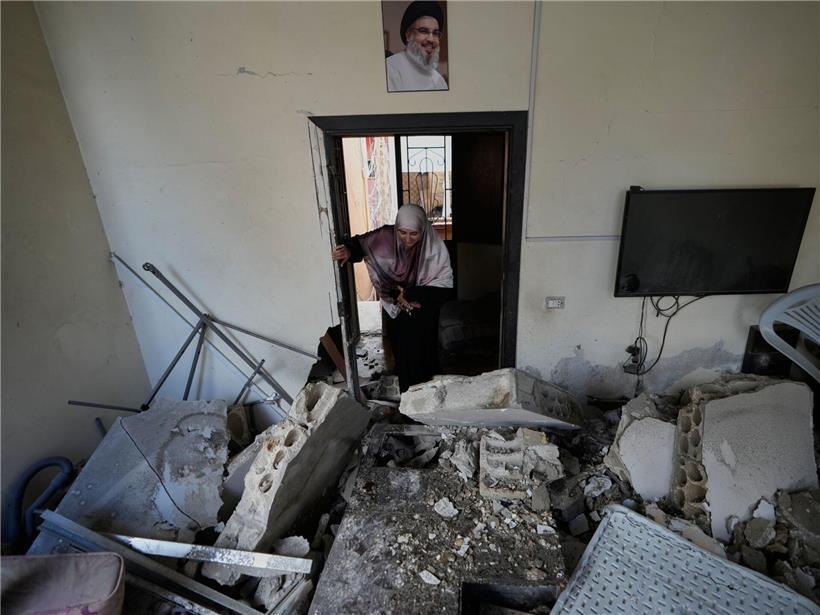 Frau betritt zerstörtes Haus nach israelischem Luftangriff, Trümmer und Schäden sichtbar, Krieg und Konflikt in Israel.