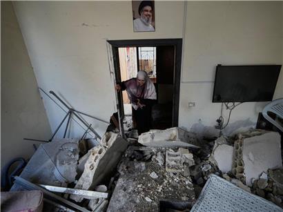 Frau betritt zerstörtes Haus nach israelischem Luftangriff, Trümmer und Schäden sichtbar, Krieg und Konflikt in Israel.