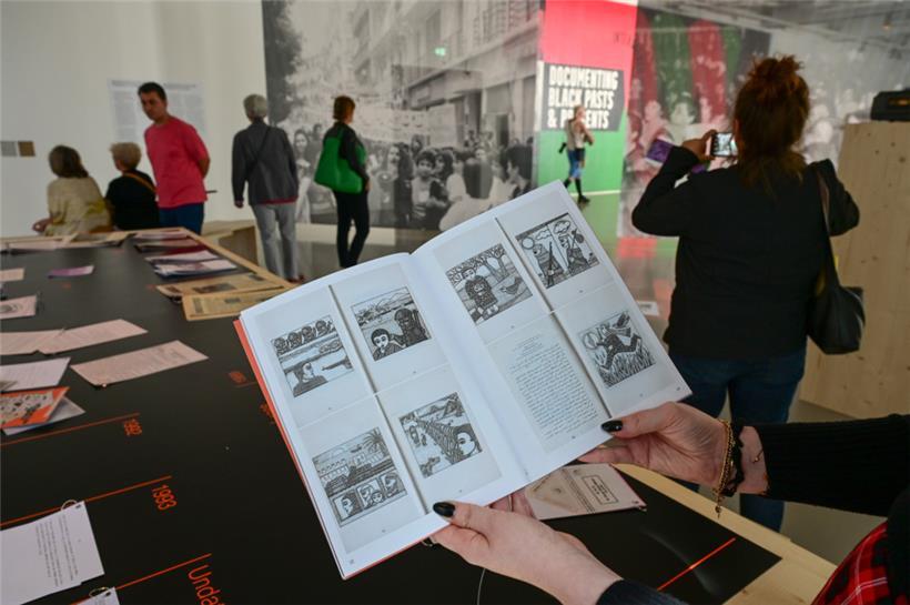 Eine Frau hält auf der documenta fifteen im Fridericianum die Broschüre mit dem Titel „Présence des Femmes“, die 1988 in Algier erschienen ist, in den Händen. Sie enthält weitere als antisemitisch kritisierte Motive. 
