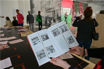 Eine Frau hält auf der documenta fifteen im Fridericianum die Broschüre mit dem Titel „Présence des Femmes“, die 1988 in Algier erschienen ist, in den Händen. Sie enthält weitere als antisemitisch kritisierte Motive. 
