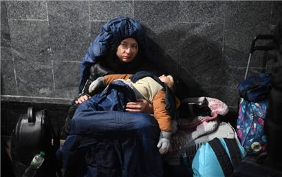 Eine Frau hält ihr schlafendes Kind im Arm, während sie am 26. Februar 2022 am Hauptbahnhof von Lwiw in der Westukraine auf dem Boden sitzt
