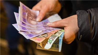 Eine Frau hält ukrainische Geldscheine in die Kamera
