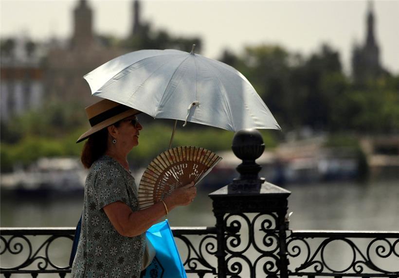 Eine Frau im spanischen Sevilla trotzt der Hitze und der drückenden Sonne
