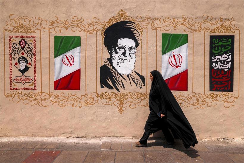 „Irans Regime fühlt sich in einer Position der strategischen Dominanz“ Eine Frau läuft in Teheran am Porträt des getöteten ehemaligen iranischen Präsidenten Ali Khamenei vorbei