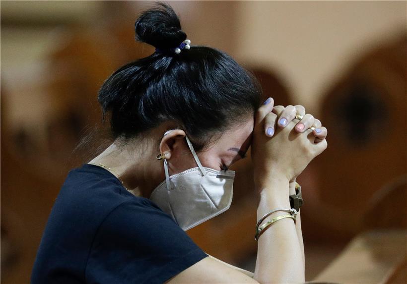 Eine Frau mit Atemschutzmaske betet während einer Messe. Die Zahl der Infektionen und Todesopfer durch die Lungenkrankheit aus China ist weltweit erneut gestiegen. 
