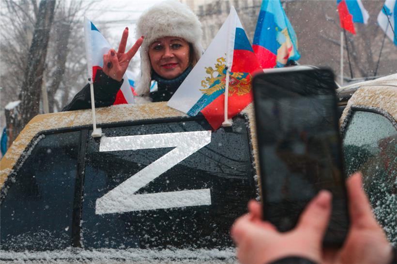 Eine Frau posiert für Fotos hinter einer Autotür, deren Fenster mit dem Buchstaben „Z“ verziert ist, der zum Symbol für die Unterstützung der russischen Militäraktion in der Ukraine geworden ist, während der Feierlichkeiten zum achten Jahrestag der russischen Annexion der Krim in Simferopol am 18. März
