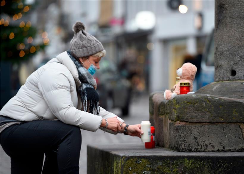 Eine Frau stellt am Trierer Hauptmarkt eine Kerze auf
