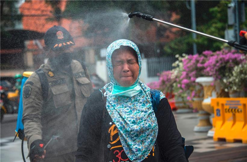 Eine Frau wird in Surabaya mit Desinfektionsmittel eingenebelt: In Indonesien werden mittlerweile 579 Fälle und 49 Tote gezählt

