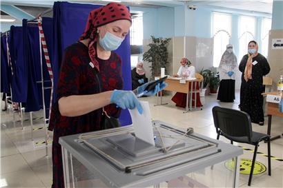 Eine Frau wirft in Grosny in einem Wahllokal ihren Stimmzettel in eine Wahlurne
