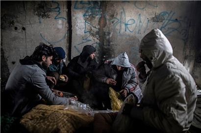 Eine Gruppe syrischer Migranten frühstückt in einem verlassenen Gebäude, in dem sie Unterschlupf gesucht hatten. Die Flüchtlinge wollen über die EU-Grenze nach Kroatien gelangen. 
