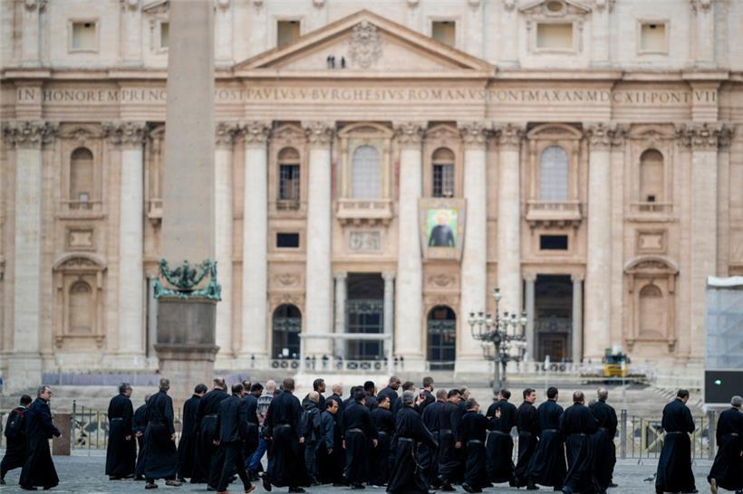 Eine Gruppe von Priestern geht am Petersdom im Vatikan vorbei
