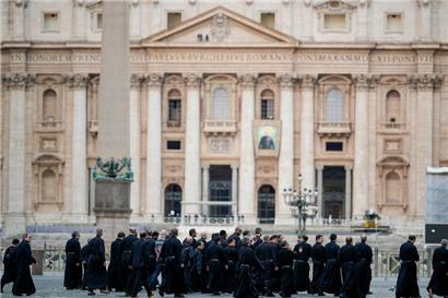 Eine Gruppe von Priestern geht am Petersdom im Vatikan vorbei
