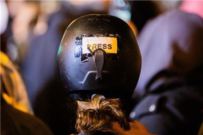 Eine Journalistin macht ihre Rolle auf einer Demonstration durch einen Aufkleber auf ihrem Helm deutlich
