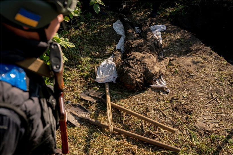 Eine Leiche liegt auf dem Boden, während Beamte im Rahmen einer Untersuchung von Kriegsverbrechen zwei Leichen aus einem Grab in einem Dorf exhumieren, das nur wenige Tage zuvor von ukrainischen Streitkräften befreit worden war. Die Behörden gaben an, dass die beiden Leichen Anzeichen von Folter aufwiesen.
