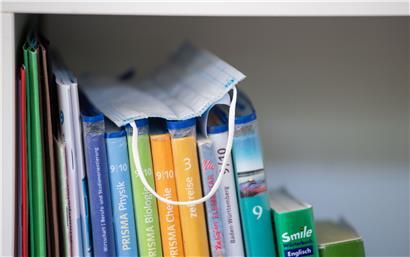 Eine Maske liegt im Bücherregal. Ein Kind, das in Quarantäne gesetzt wird, muss zu Hause betreut werden können. Deshalb wurde für zwei bestimmte Fälle ein zusätzlicher Sonderurlaub vorgesehen. 

