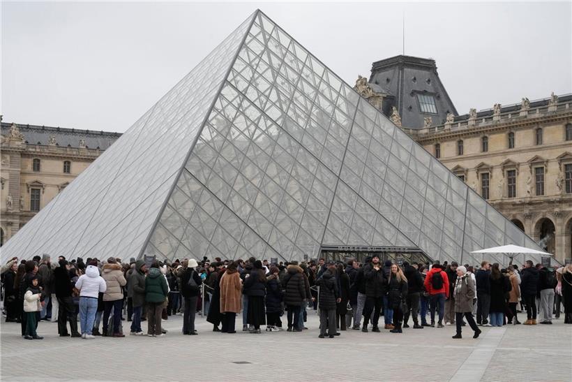 Menschenmenge steht in Warteschlange vor dem historischen Louvre Museum in Paris bei klarem Himmel