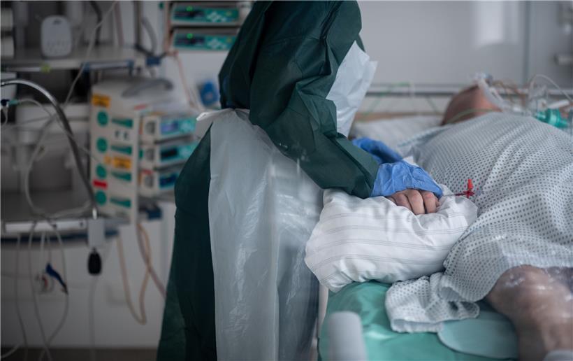  Eine Mitarbeiterin der Pflege in Schutzausrüstung betreut einen Corona-Patienten
