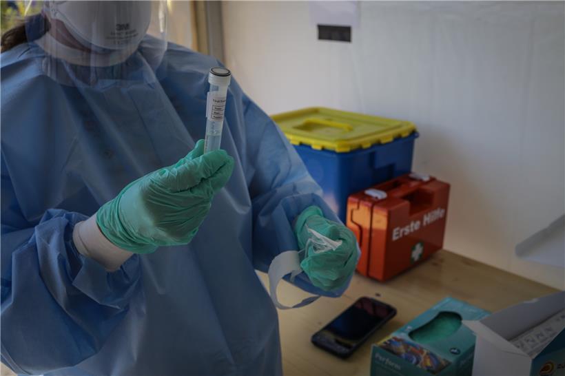 Eine Mitarbeiterin in einem Covid-19-Testzentrum beschriftet eine Ampulle mit einem Abstrichstäbchen
