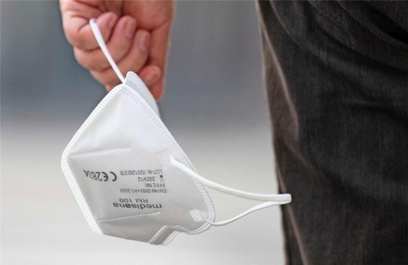 Eine Passantin trägt eine FFP2-Maske in der Hand
