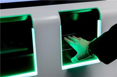 Eine Person legt am Flughafen Düsseldorf die Hand auf einen Scanner zur Erfassung biometrischer Daten
