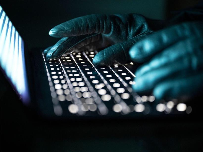 Person mit Handschuhen tippt auf beleuchtete Laptop-Tastatur, Arbeit im Dunkeln, ergonomisches Tippen, Technologie nutzen