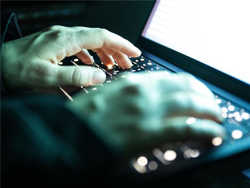 Person tippt auf beleuchtete Laptop-Tastatur, Arbeiten am Computer, digitales Schreiben, Tastaturbeleuchtung bei Nacht