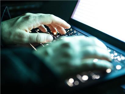 Person tippt auf beleuchtete Laptop-Tastatur, Arbeiten am Computer, digitales Schreiben, Tastaturbeleuchtung bei Nacht