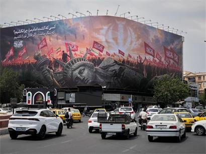 Eine Plakatwand, auf der eine umgestürzte Freiheitsstatue und Menschenmengen mit iranischen und schiitischen Flaggen zu sehen sind, überragt den Revolutionsplatz in der iranischen Hauptstadt