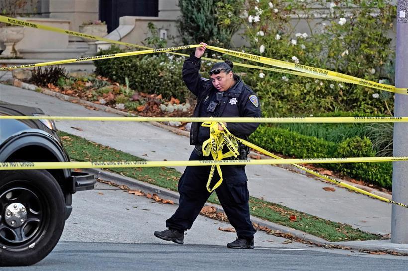 Eine Polizistin blockiert mit gelbem Absperrband die Straße unterhalb des Hauses von Paul Pelosi
