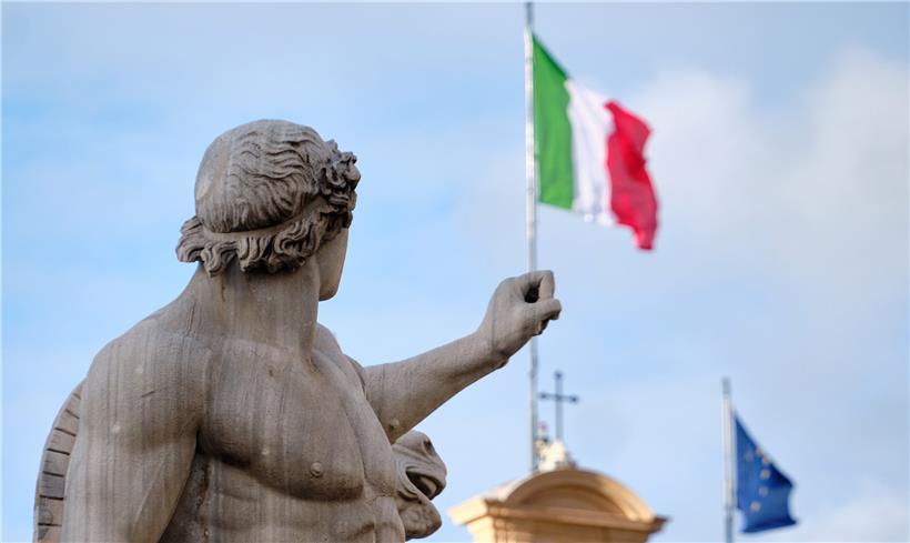 Eine Statue steht vor dem Palazzo del Quirinale in Rom, dem Sitz des Präsidenten von Italien, auf dessen Dach die Flaggen Italiens und der EU wehen
