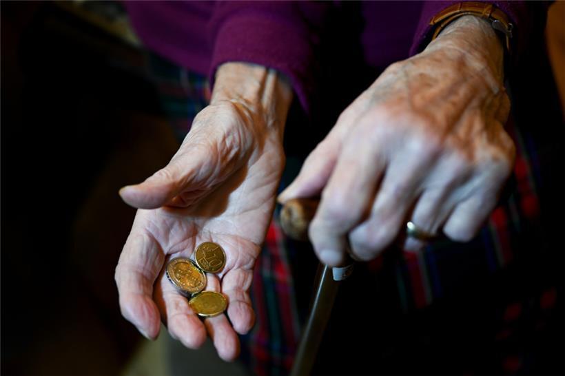 Eine alte Frau hält Kleingeld in der Hand
