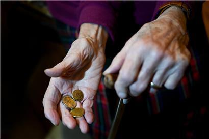Eine alte Frau hält Kleingeld in der Hand
