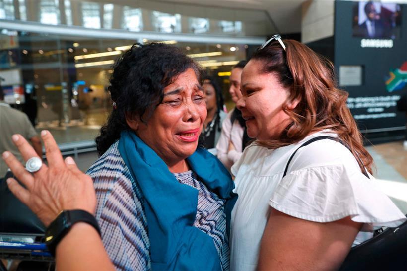 Eine aus dem Sudan geflüchtete Südafrikanerin (links) weint, als sie von einem Familienmitglied nach ihrer Ankunft am OR Tambo International Airport in Johannesburg am 30. April 2023 begrüßt wird
