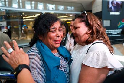 Eine aus dem Sudan geflüchtete Südafrikanerin (links) weint, als sie von einem Familienmitglied nach ihrer Ankunft am OR Tambo International Airport in Johannesburg am 30. April 2023 begrüßt wird
