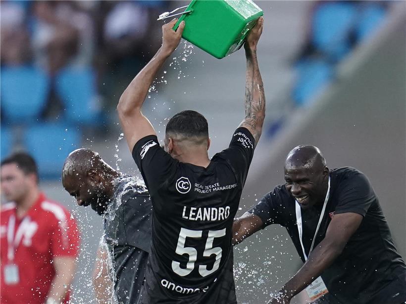 Trainer steht unter kaltem Wasserstrahl in der Dusche, erfrischende Abkühlung nach dem Training