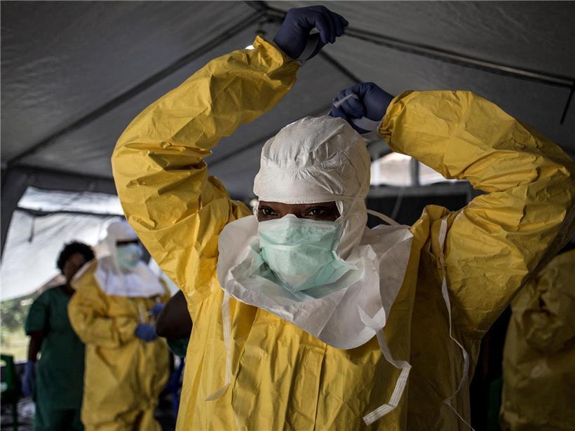 Medizinische Fachkraft zieht persönliche Schutzausrüstung an vor Ebola-Behandlungszentrum für Infektionsschutz