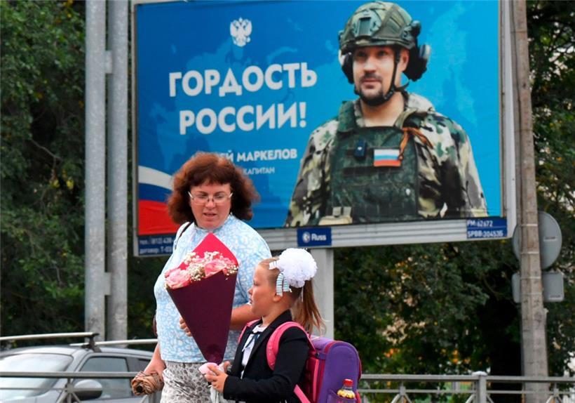 Eine russische Schülerin geht am ersten Tag des neuen Schuljahres in Sankt Petersburg an einem Plakat zu Ehren eines russischen Soldaten vorbei

