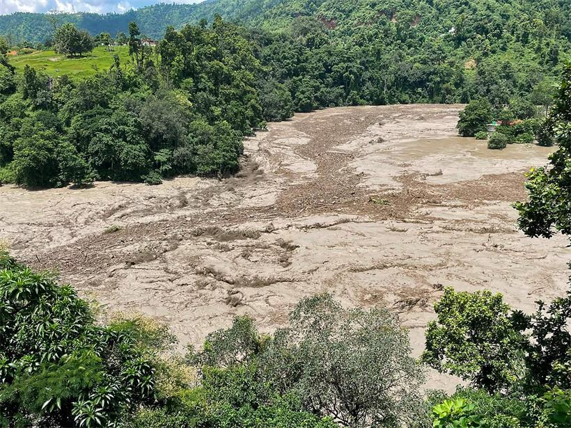 Eine schlammige Flutwelle reißt am 26. August 2026 nach Sturzfluten in Galchhi im nepalesischen Distrikt Dhading durch einen Fluss